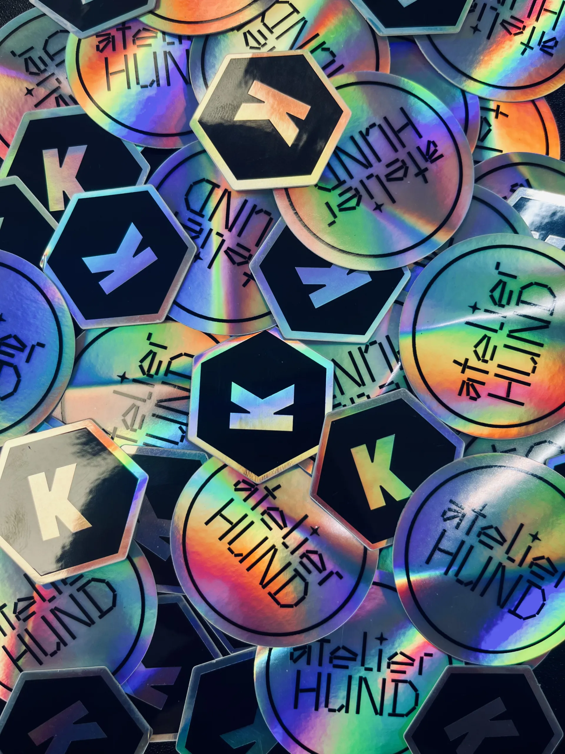 Sticker in Holo-Optik mit dem Kirby Logo und dem Atelier Hund Logo