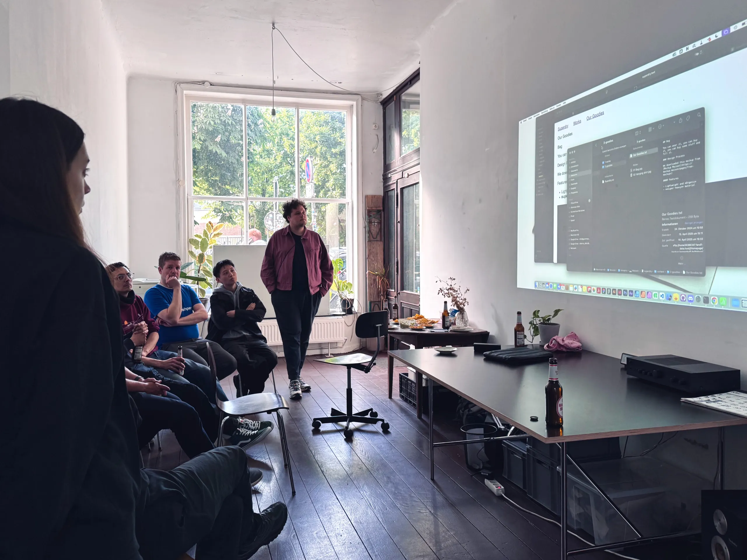 Menschen in einem Atelier schauen auf eine Leinwand, auf die eine Benutzeroberfläche projiziert wird.