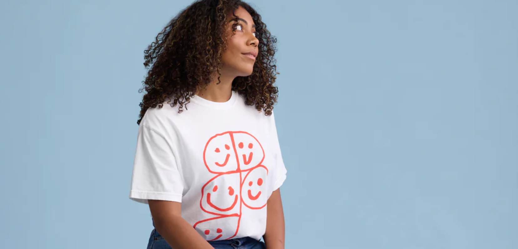 Eine Frau die ein weißes Tshirt trägt. Auf dem Tshirt befindet sich das Figma Logo mit vielen lächelnden Gesichtern in den einzelnen Flächen